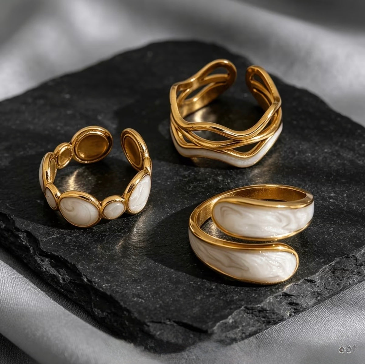 Three gold-toned statement rings with white marbled stone inlays.