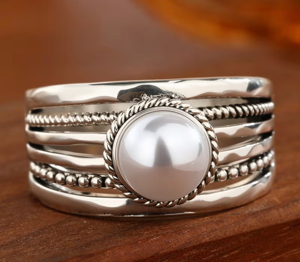 A sterling silver multi-band ring featuring a large, lustrous white pearl in the center.